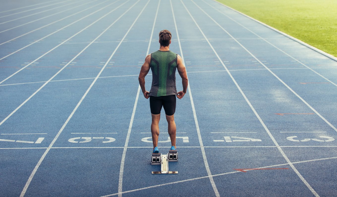 Sprinter Standing on Starting Block on Running Track